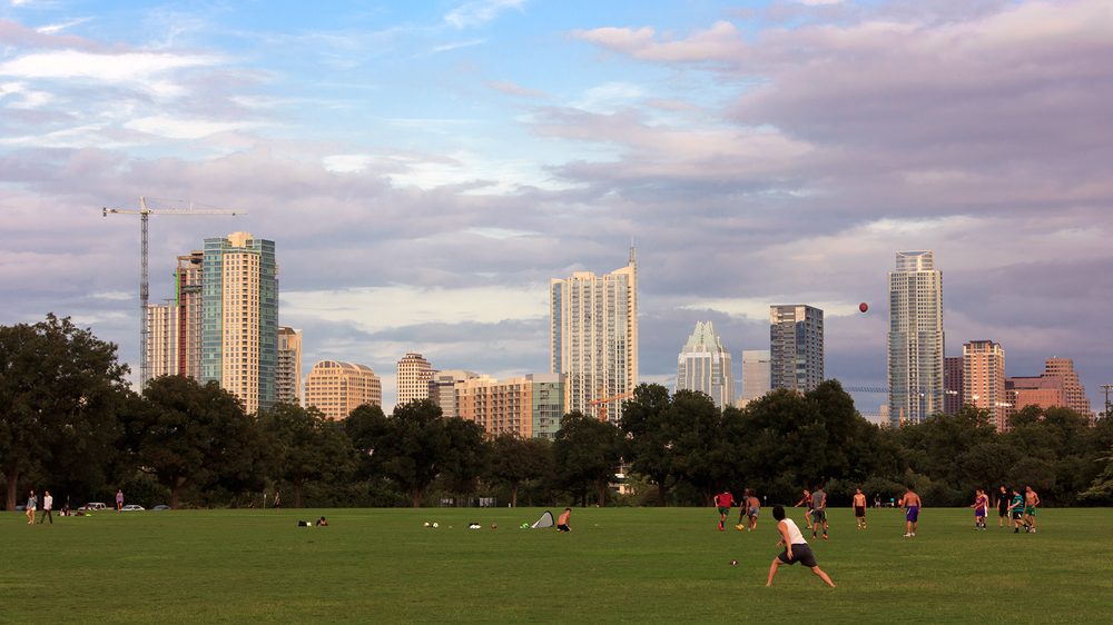 The green lawn of Zilker Park with the Austin skyline beyond