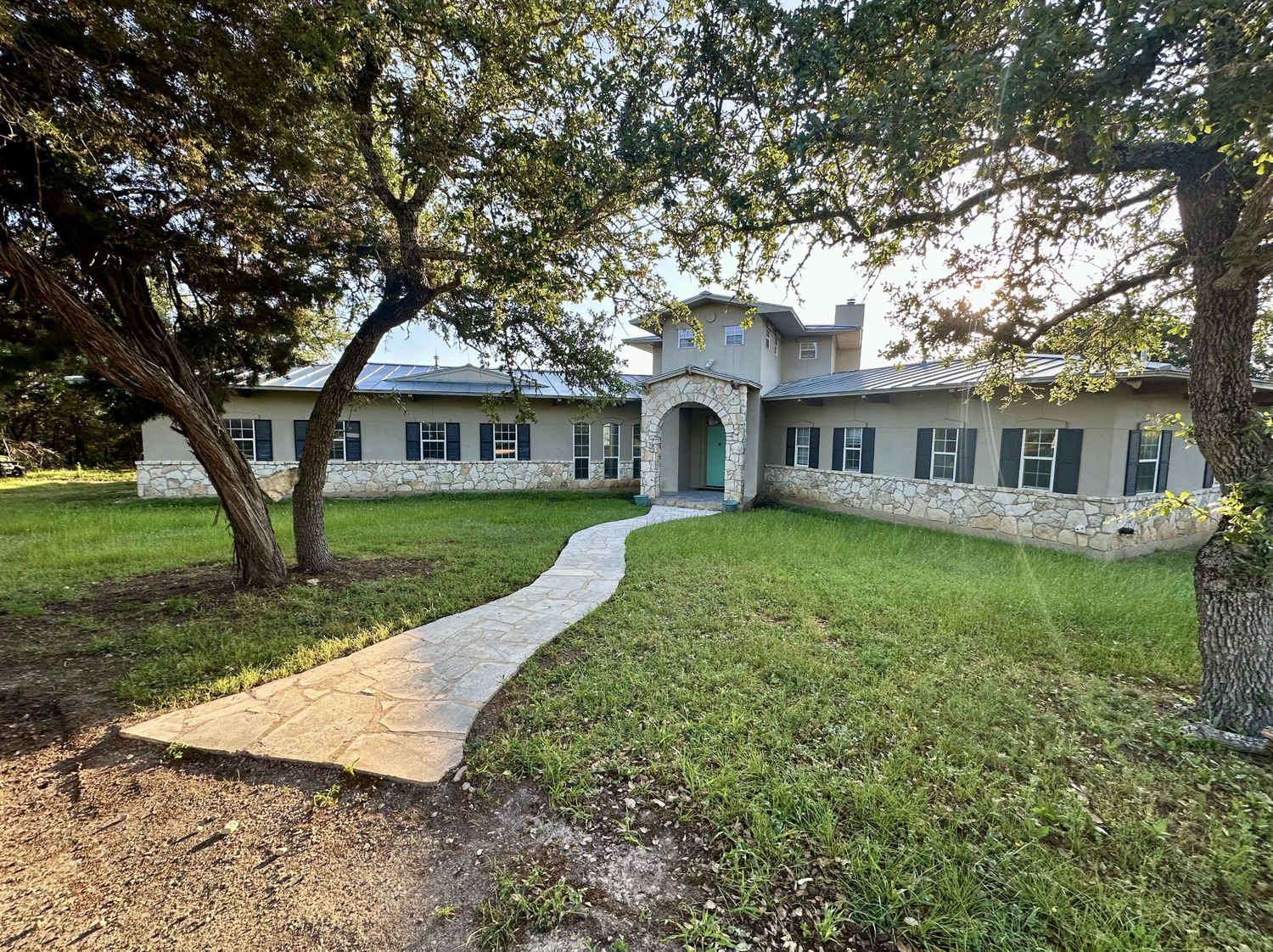 The stone sanctuary house framed by hill country oaks