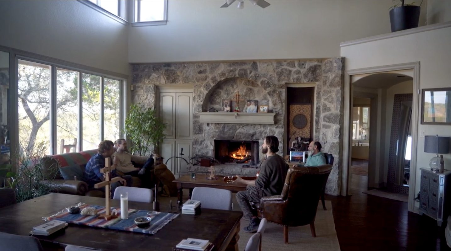 The great room with a lit stone fireplace where guests gather and talk
